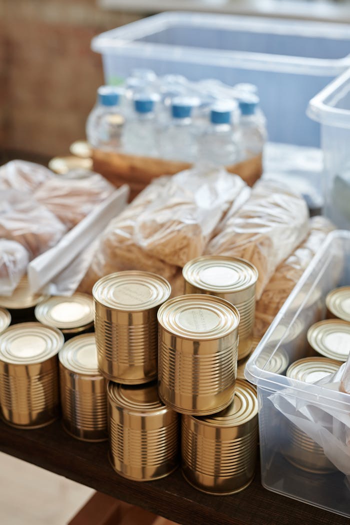 who-we-are A variety of canned goods and packaged items arranged for a donation drive or food bank collection.