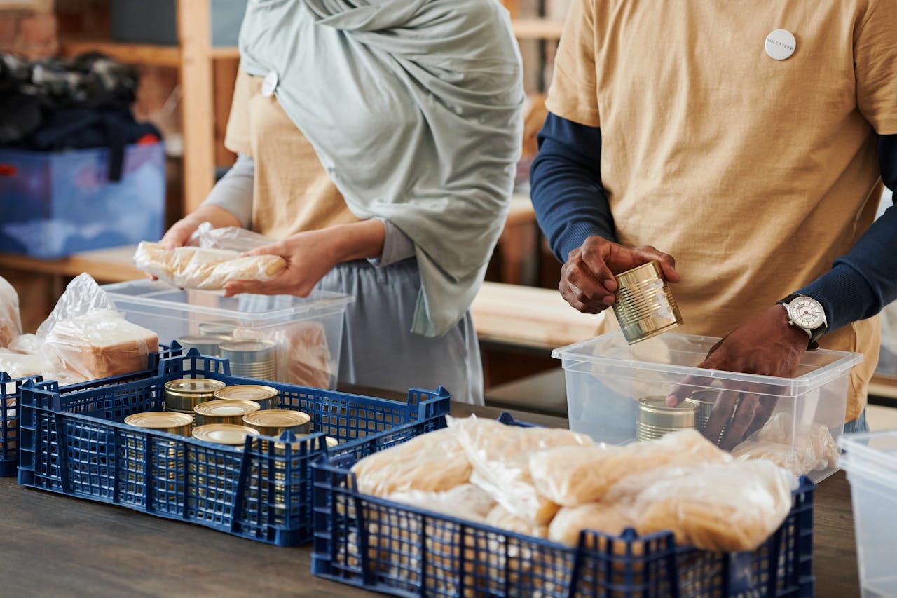 services-01 Adults sorting food donations in containers for charity. Community service effort indoors.